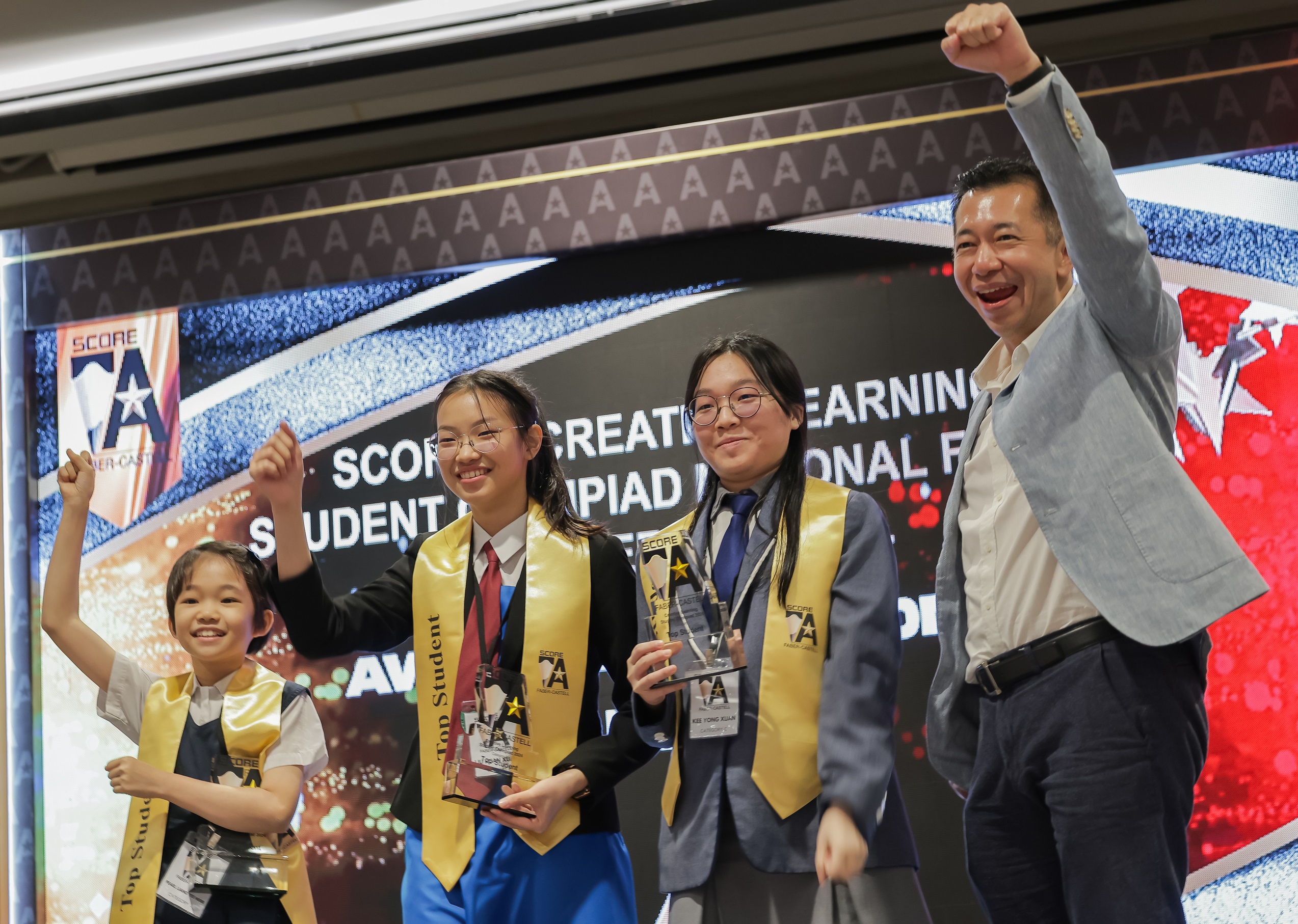 Mr. Andrew Woon, Managing Director of Faber-Castell Malaysia, with the Score A Creative Learning Student Olympiad Top Students across all categories, Pearl Liang Yee Herr, Liu Huan Xuan and Kee Yong Xuan (Standing, left to right).